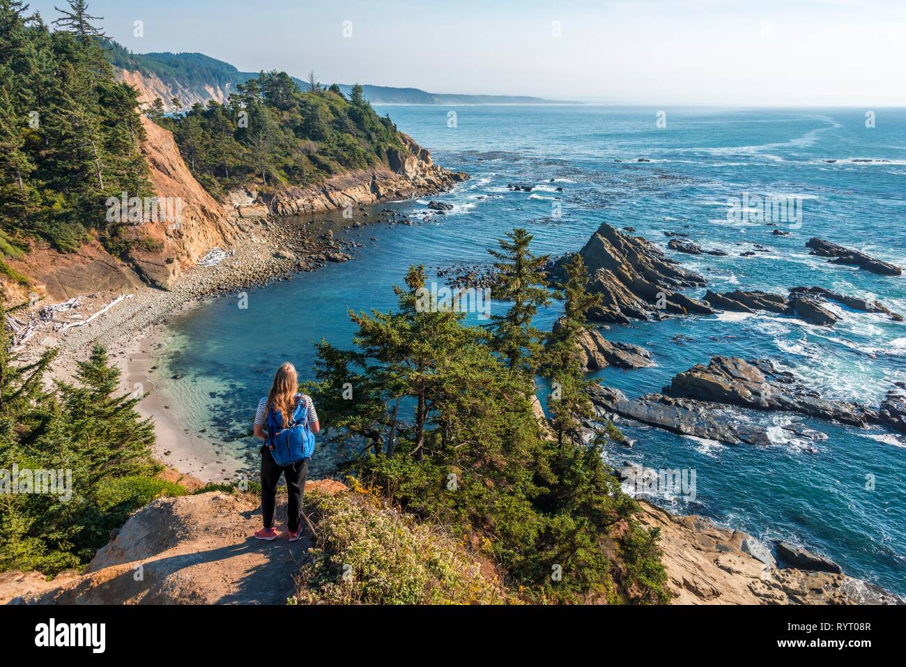 Mujer joven con mochila, caminante contemplando el paisaje costero con rocas escarpadas, Samuel H. Boardman Estado Corredor escénico Foto de stock