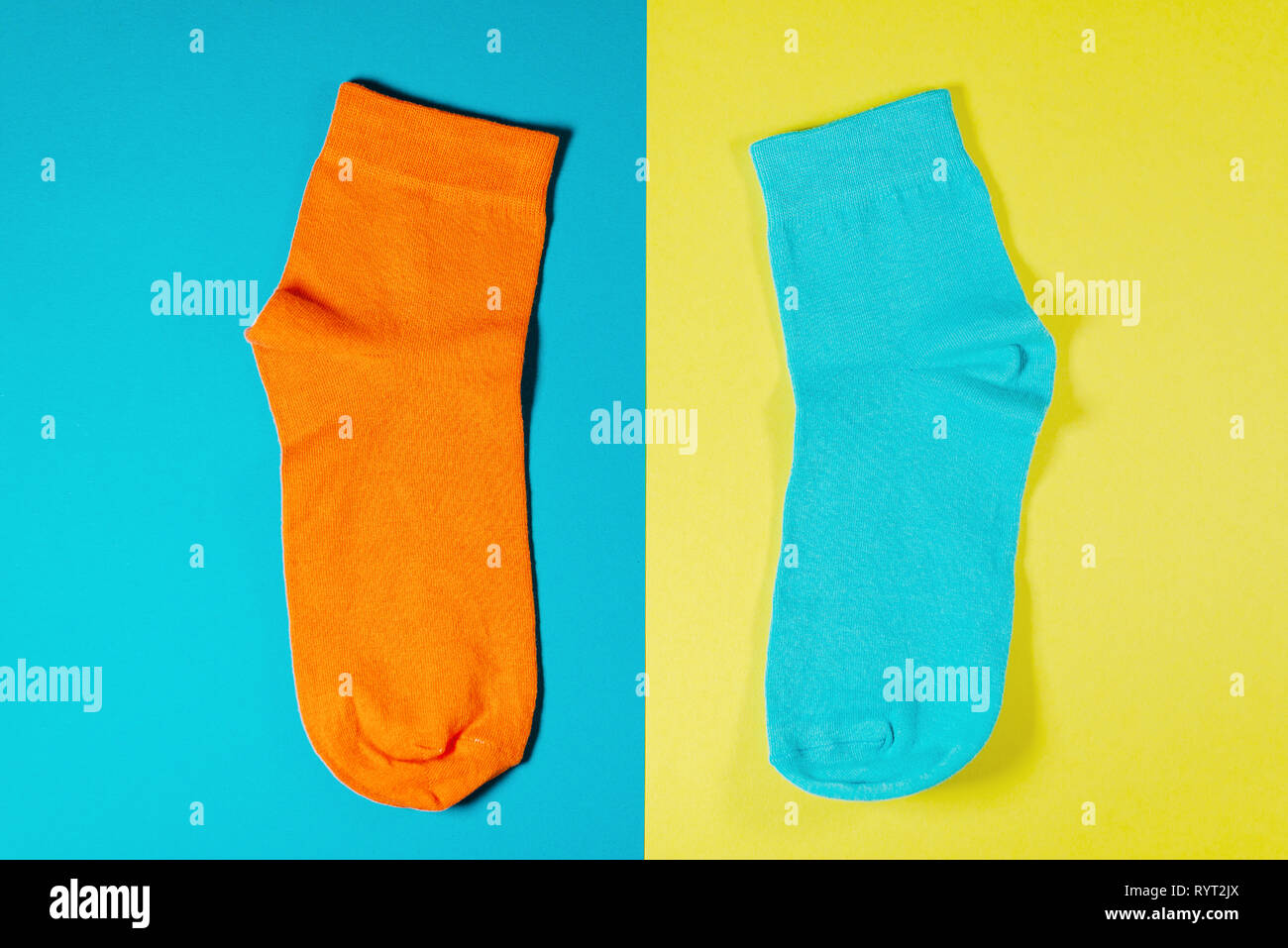 Nuevo par de calcetines naranja, azul sobre un fondo amarillo Foto de stock