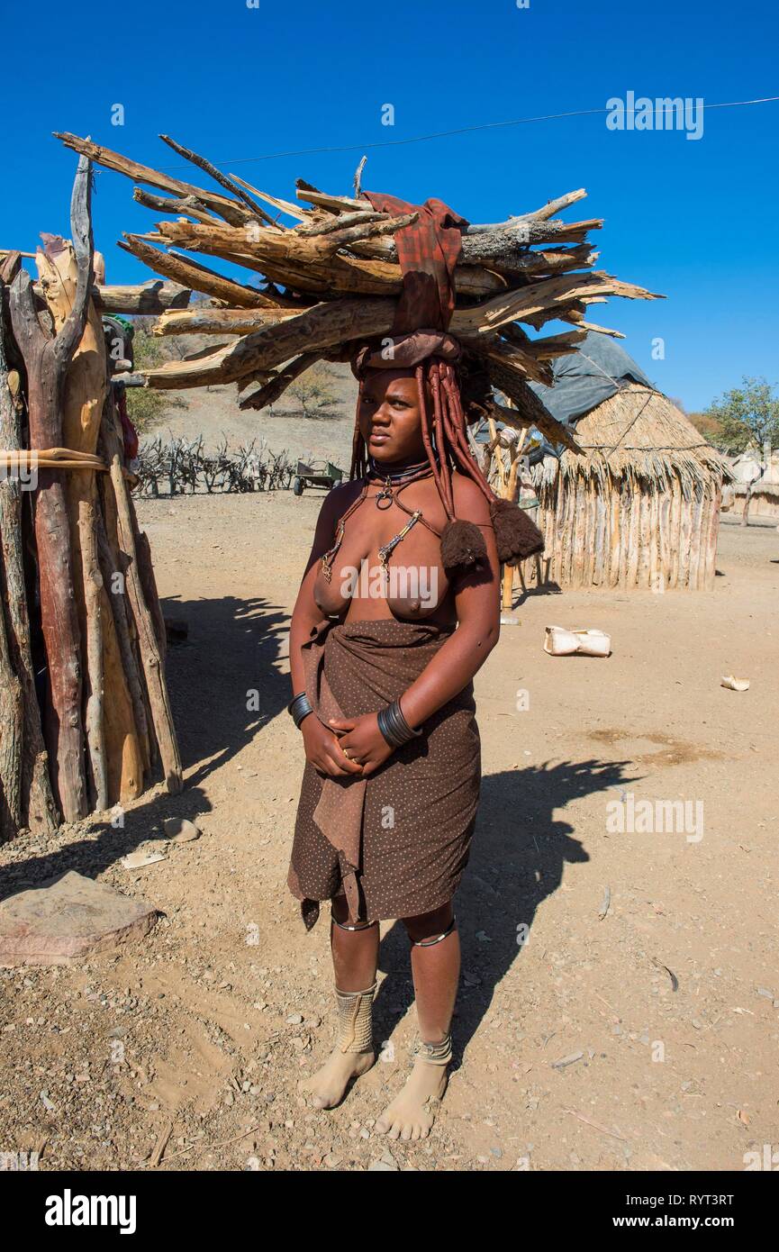 Mujer Himba transportaban madera sobre su cabeza, Kaokoland, Namibia Foto de stock