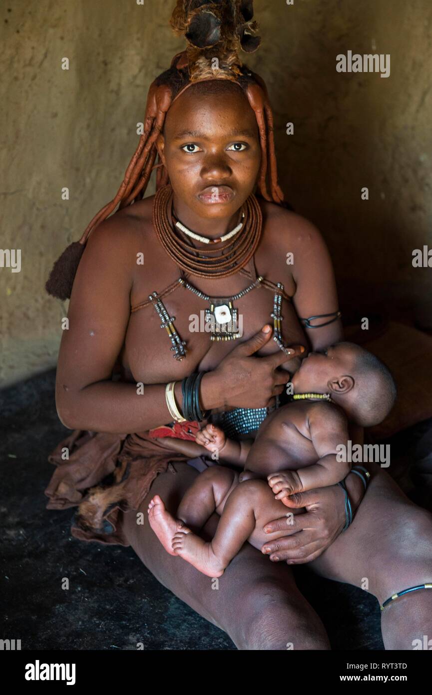Himbas mujer amamantando a su bebé, Kaokoland, Namibia Foto de stock