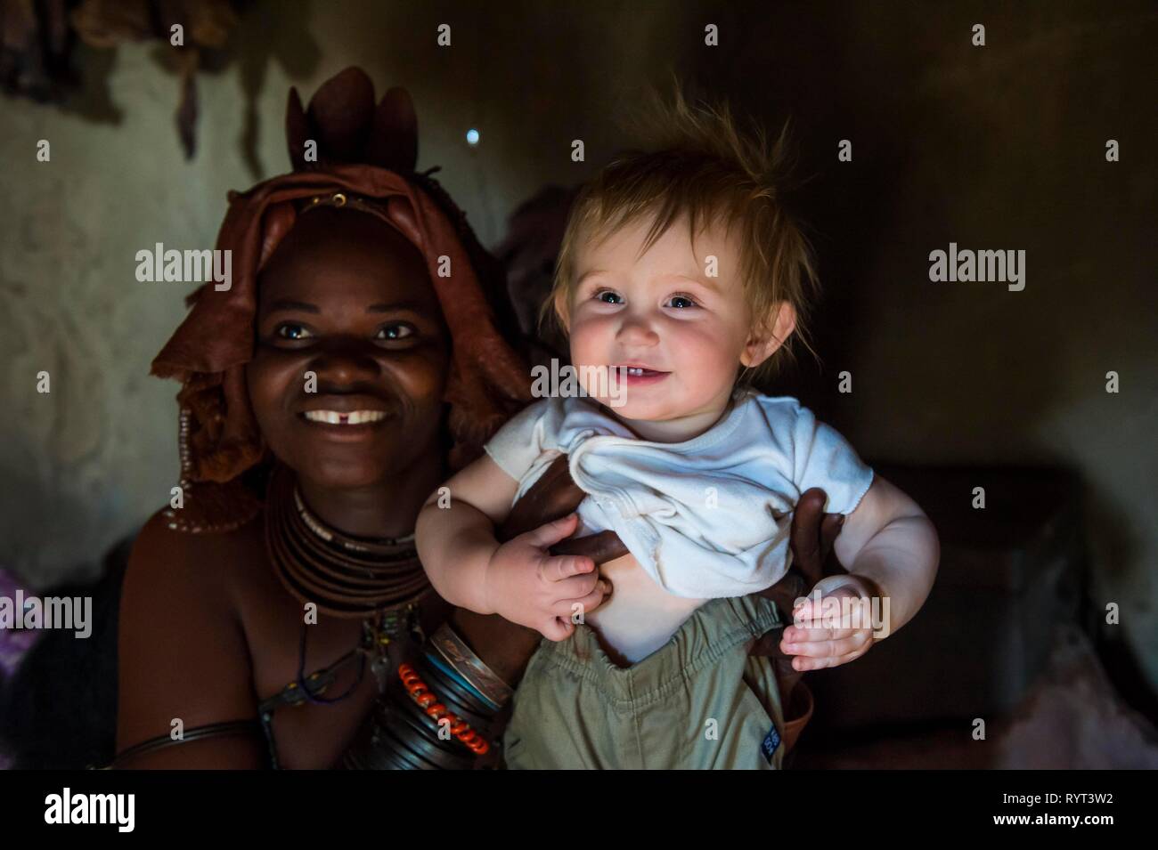 Himbas mujer sosteniendo un turista blanco bebé, Kaokoland, Namibia Foto de stock