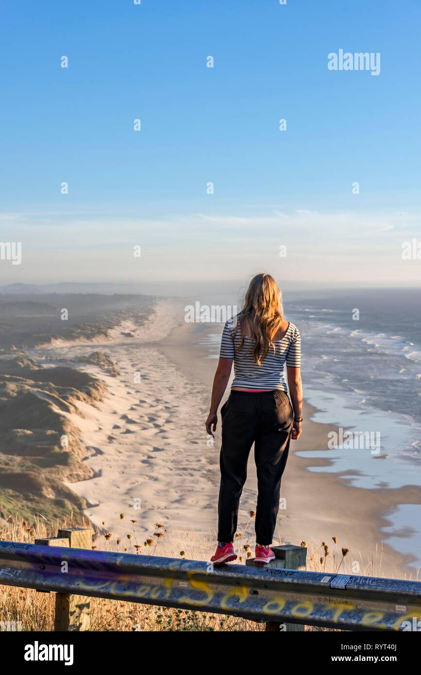 Mujer joven mirando en la distancia a un punto de vista, opinión sobre Baker Beach, Oregon Coast Highway, Oregón, EE.UU. Foto de stock