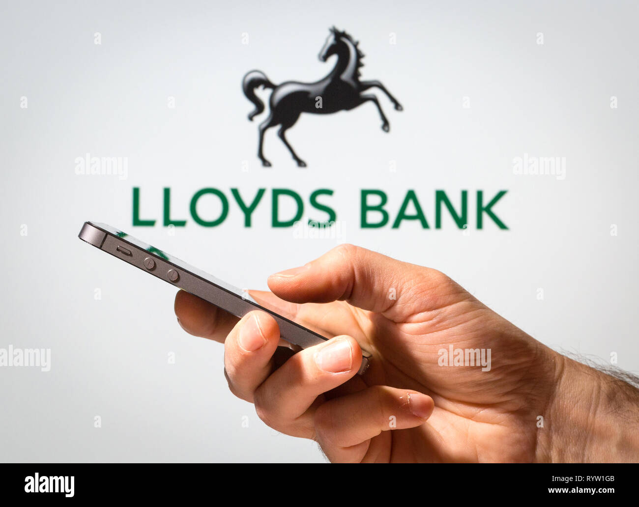 Un hombre usando Lloyds Bank banca en línea en su teléfono móvil Foto de stock