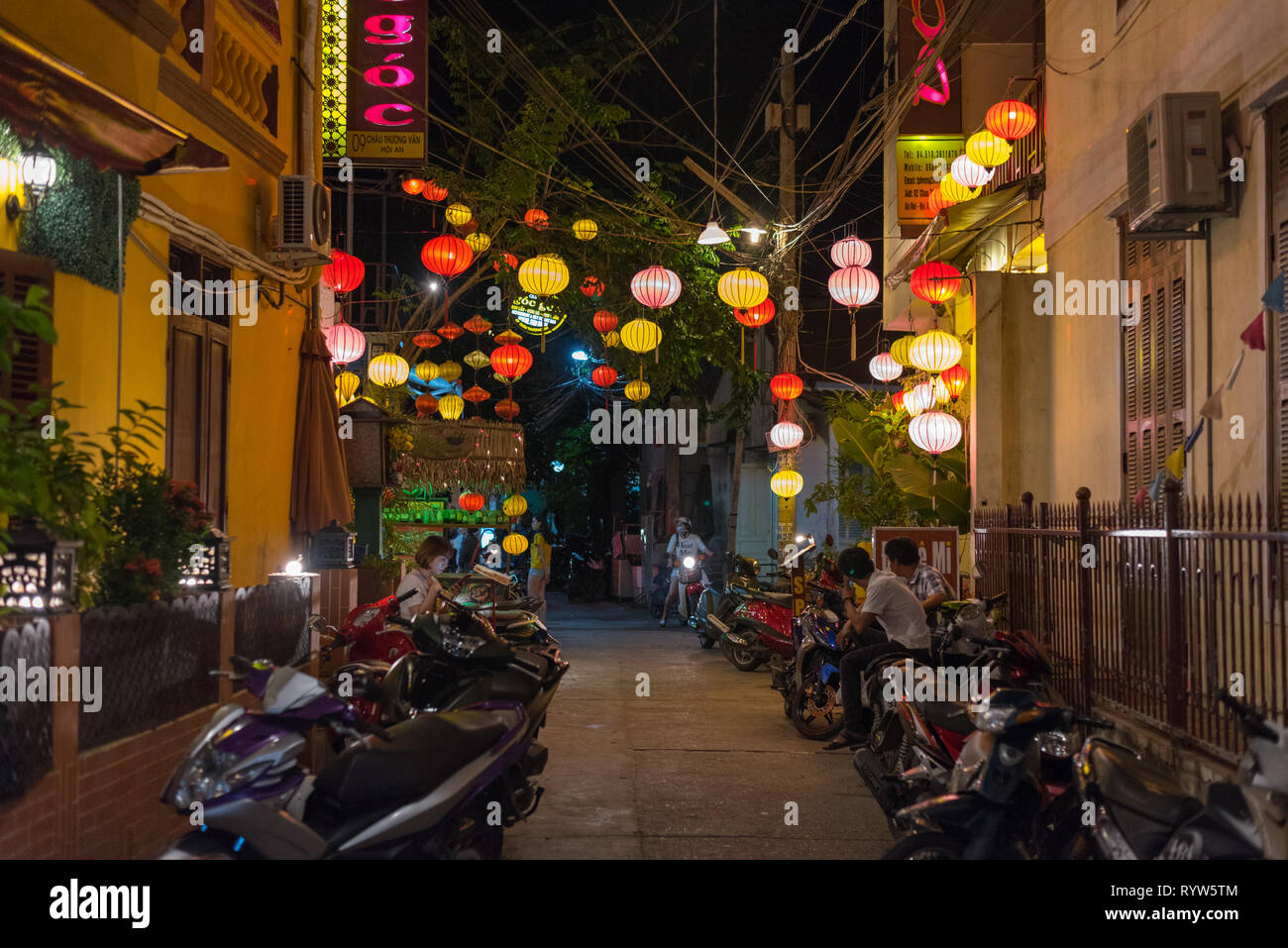 Hoi An, Vietnam - Noviembre 13, 2018: una noche backstreet están decoradas con coloridos faroles de papel con motos aparcadas y a varias personas. Foto de stock