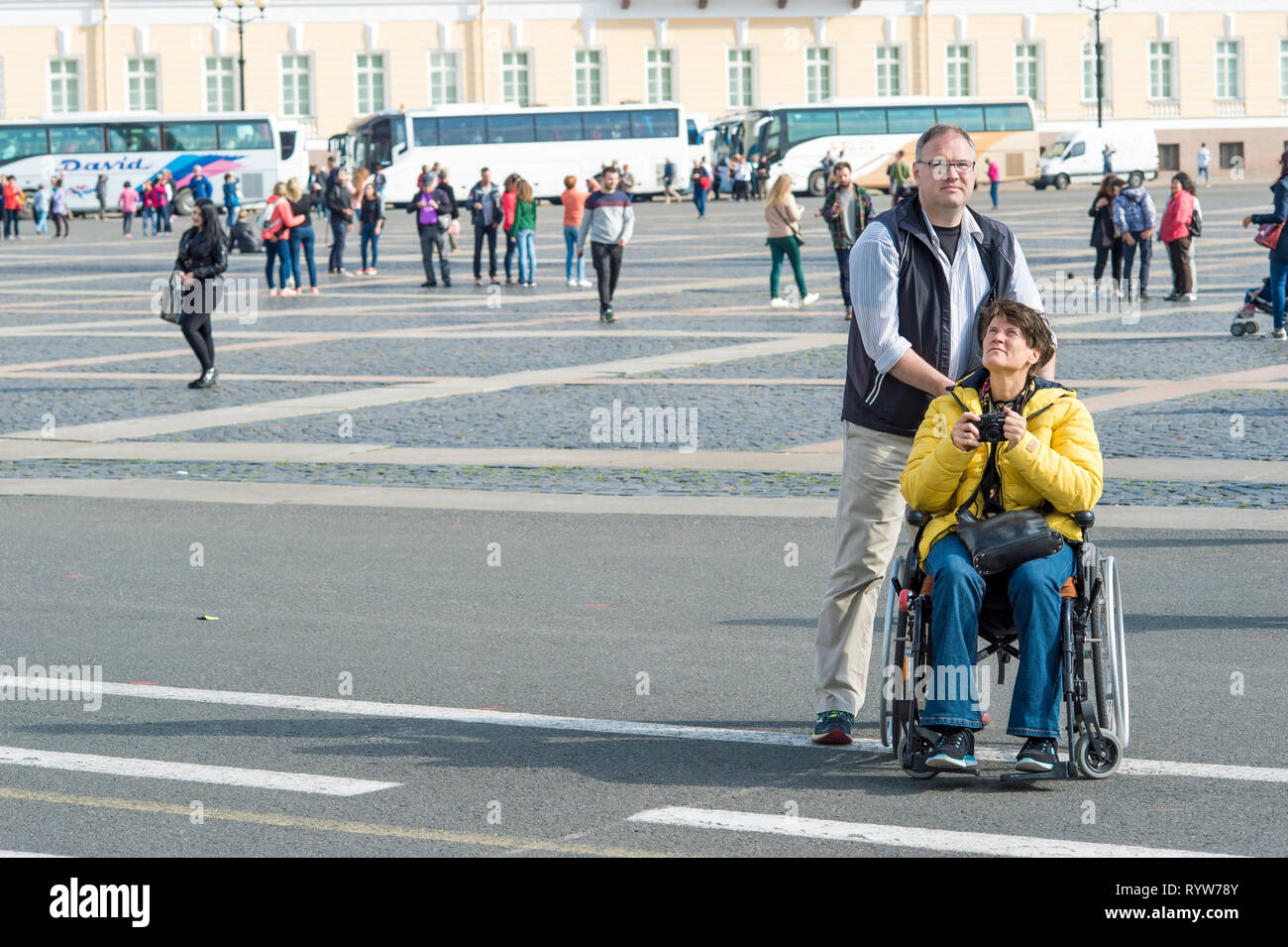 El hombre lleva una mujer caucásica en una silla de ruedas en un viaje a la plaza del Palacio de San Petersburgo, Rusia, en septiembre de 2018, Foto de stock