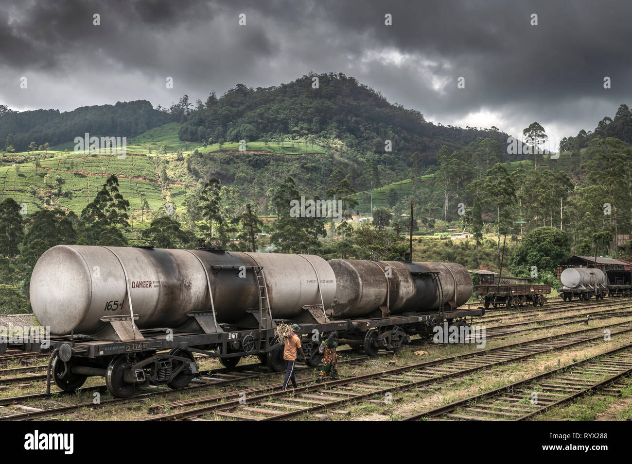Un par de caminar a lo largo de las pistas de la estación, como tormenta Nanu-Oya c;louds reunir sobre las colinas en la Provincia Central de Sri Lanka, utilizando el ferrocarril lin Foto de stock