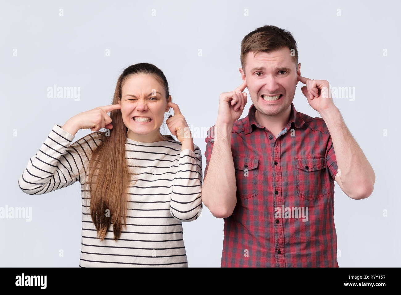 Unión familia joven pareja hombre y mujer cerrando los oídos porque de ruidos desagradables. Foto de stock