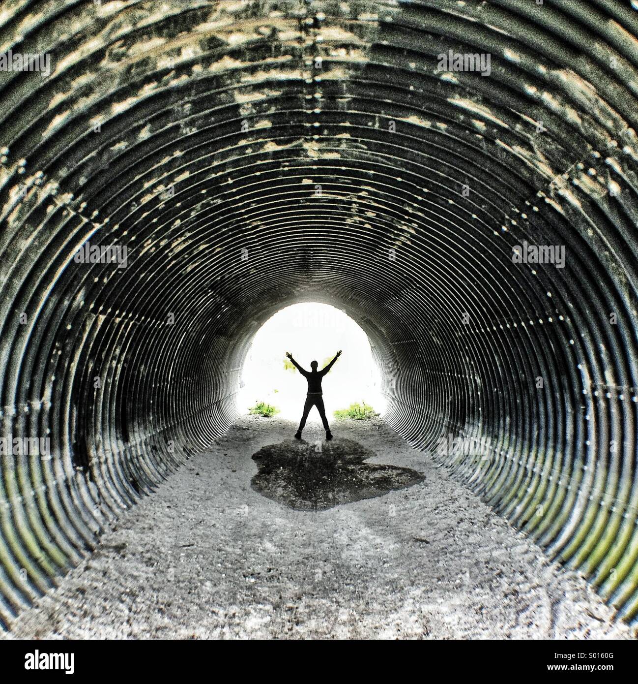 Mujer brazos estirados en túnel de metal corrugado. Foto de stock