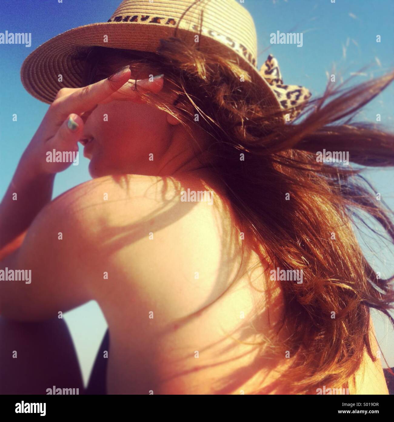 Hermosa mujer joven con largo cabello oscuro y sombrero en la playa Foto de stock