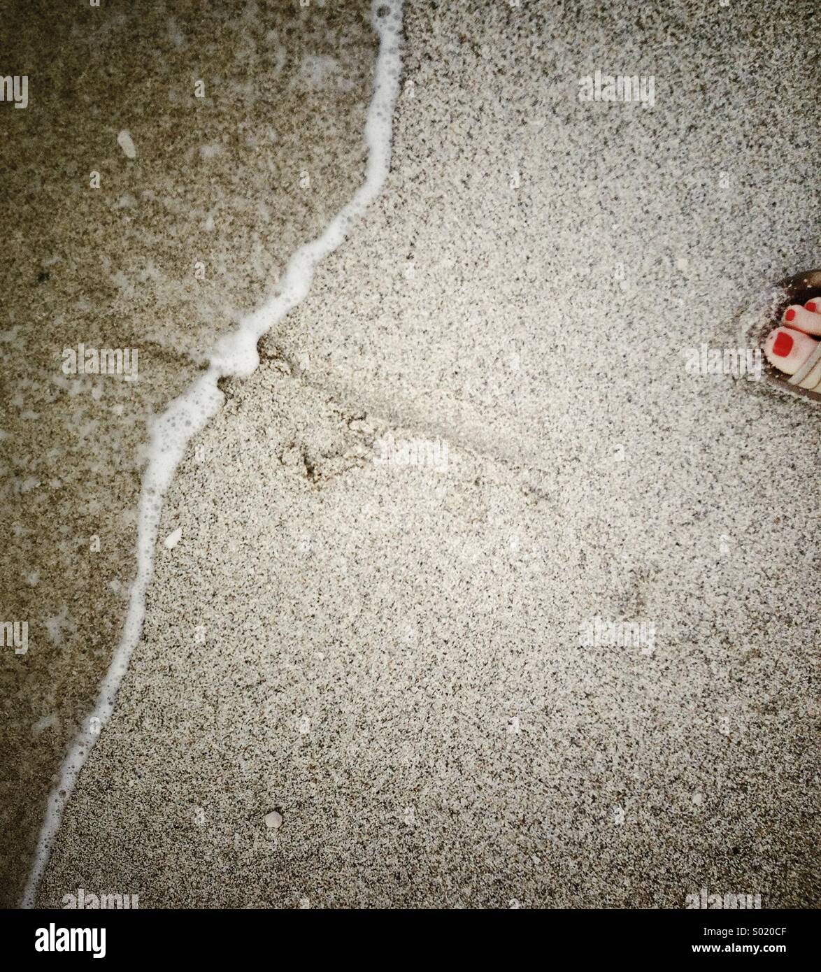 Retroceder desde el borde del agua en la playa. Sólo un dedo.... Foto de stock