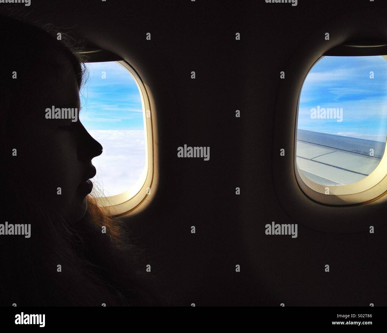 Los viajes aéreos, en el perfil de una adolescente por la ventana del avión en vuelo Foto de stock