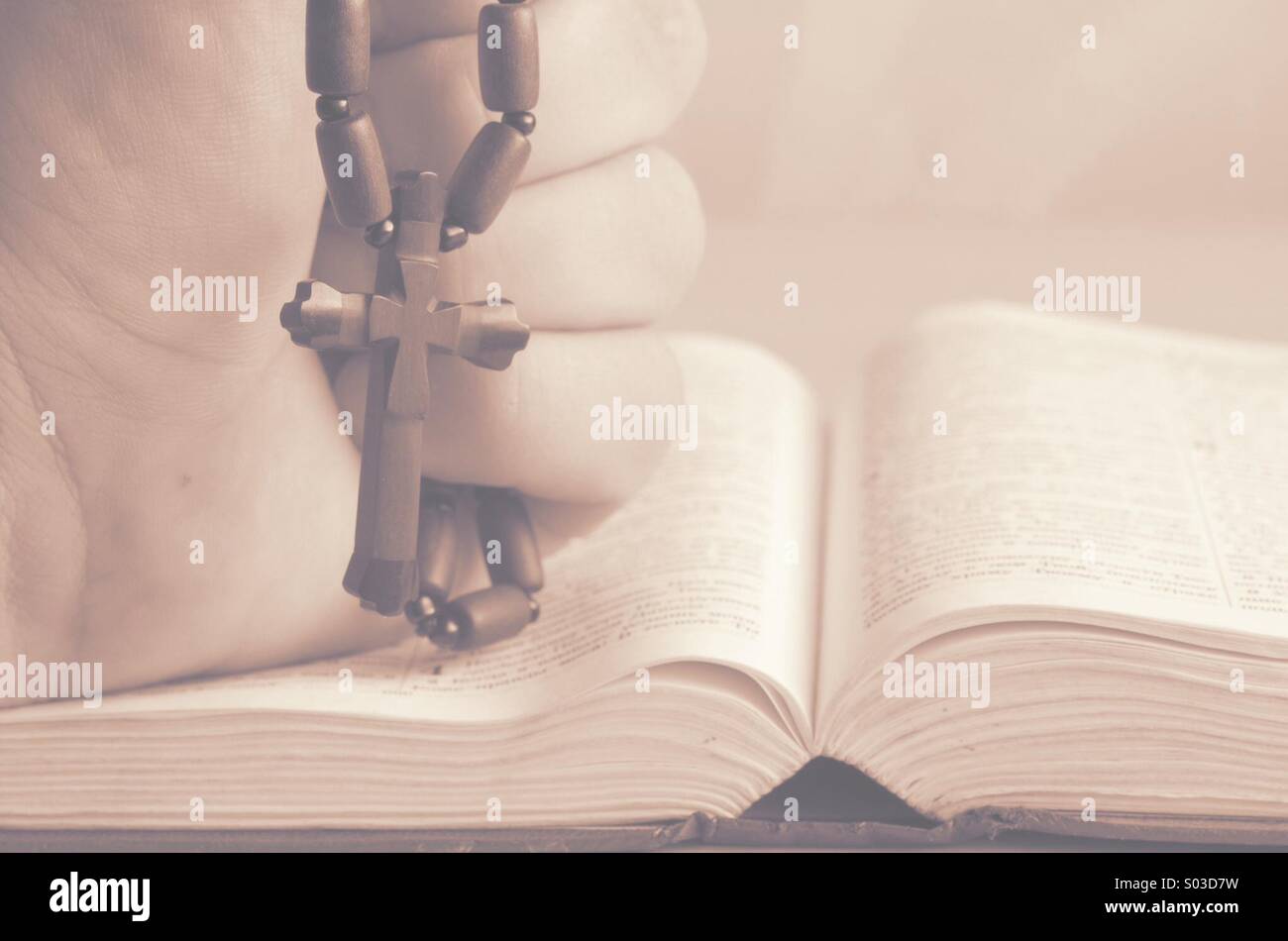 Crucifijo de madera en la mano sobre la biblia. Foto de stock