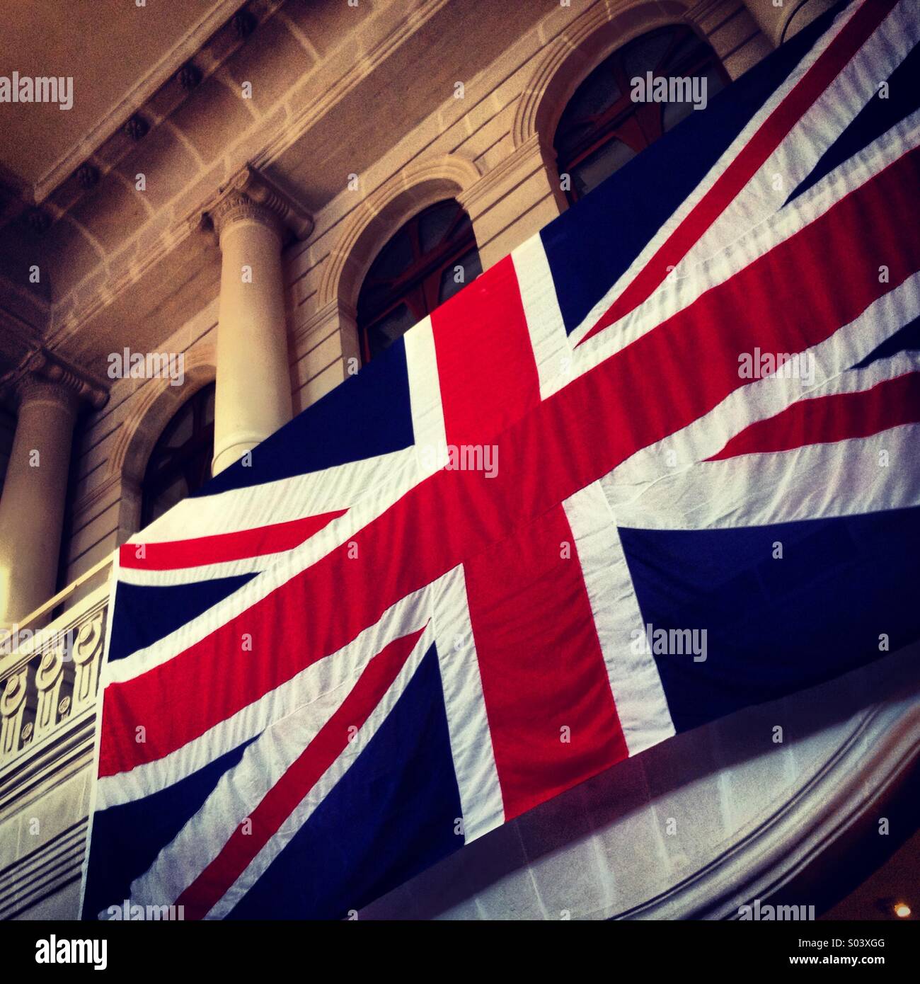 Union Jack británica bandera colgada en edificio clásico. Foto de stock