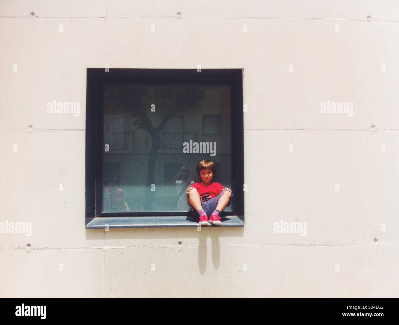 Muchacho sentado en una ventana Foto de stock