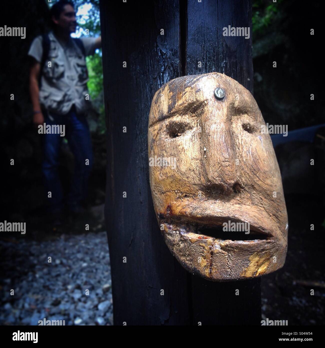 Un hombre posee una imagen detrás de una máscara de madera en un