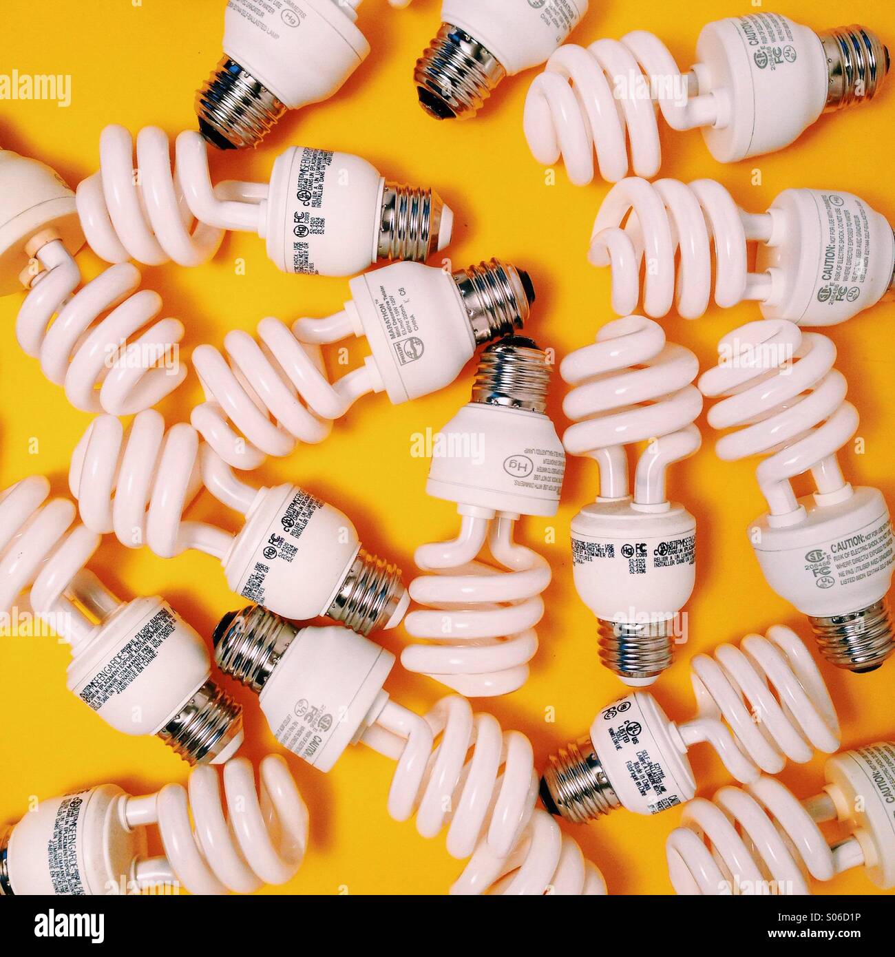 Un montón de bombillas CFL sobre un fondo amarillo Foto de stock