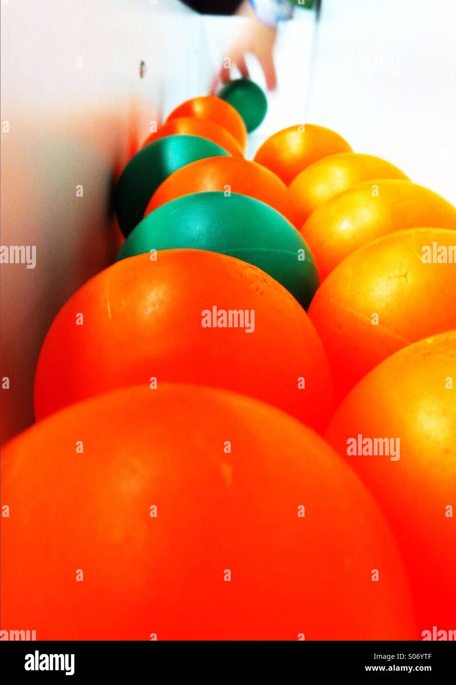 Las bolas de color naranja y verde y de la mano de un niño agarra una bola verde Foto de stock