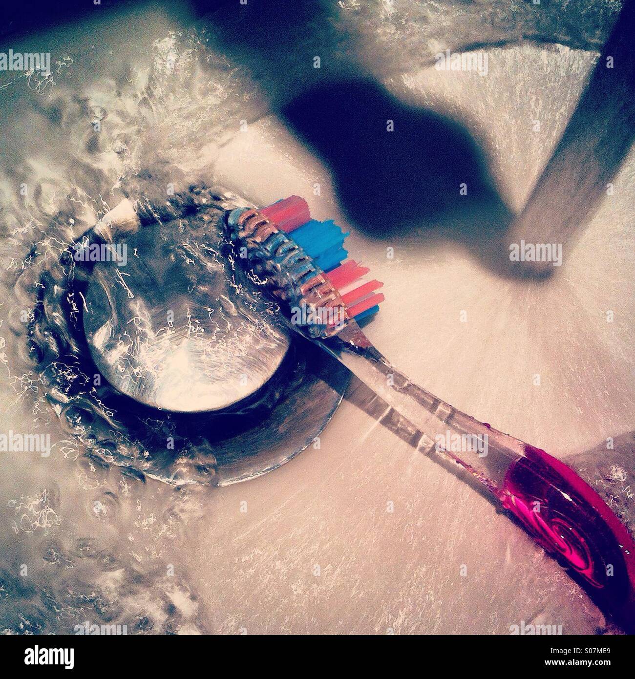 Limpiar el cepillo de dientes en el fregadero. Foto de stock