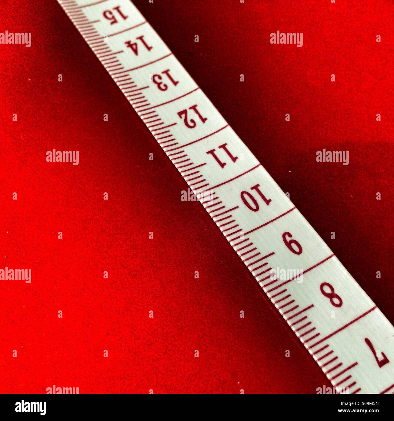 Cinta métrica mostrando centímetros sobre un fondo rojo. Foto de stock