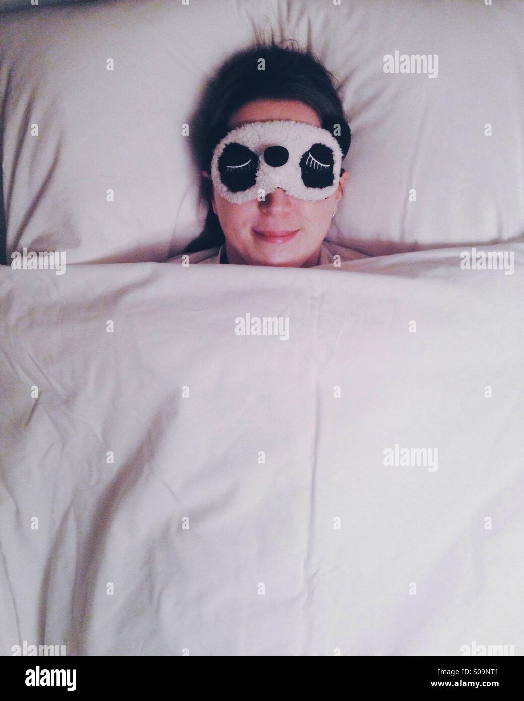 Chica en la cama durmiendo con máscara de ojo Foto de stock