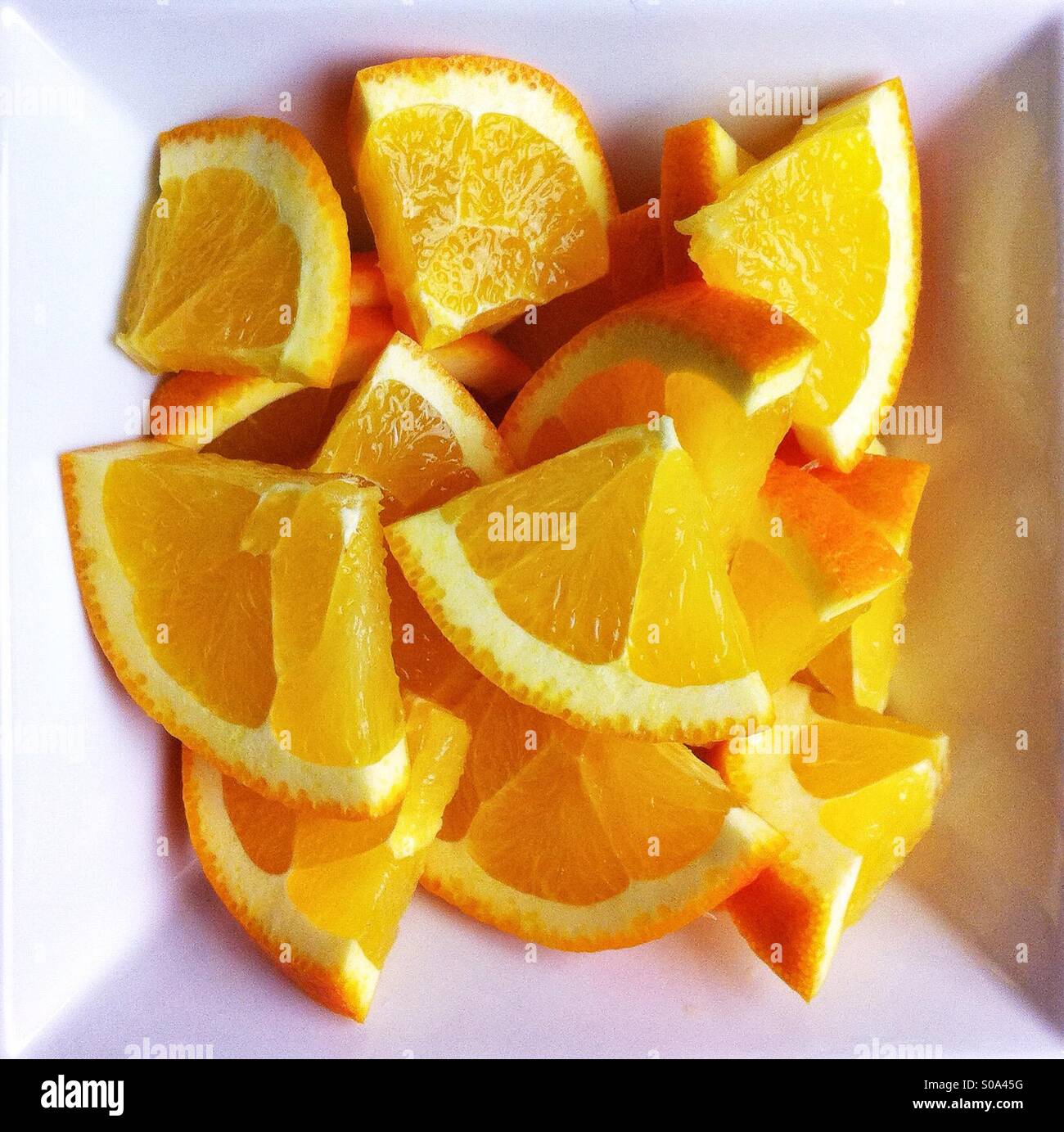 Acuartelados en las rodajas de naranja en el cuadrado blanco bowl Foto de stock