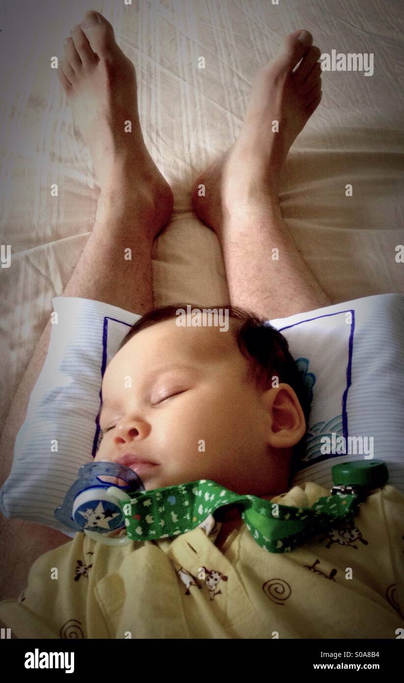 Hermosa niña durmiendo en las piernas de su padre Foto de stock