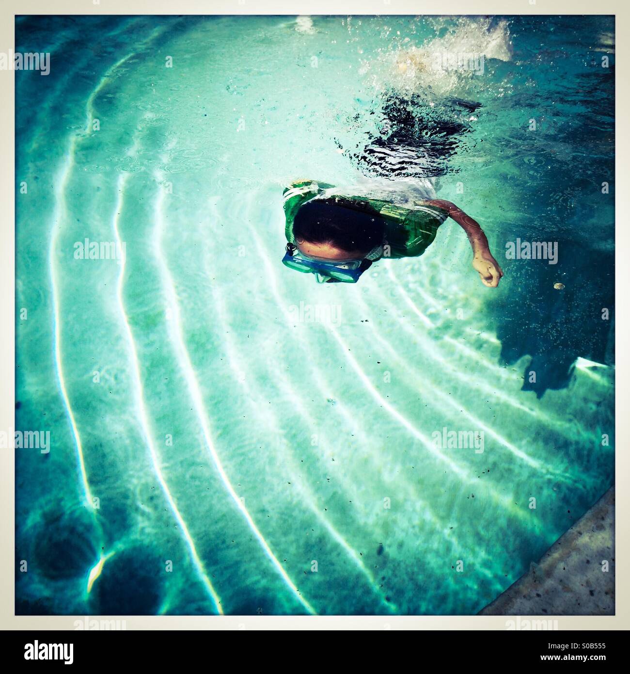 Un niño de siete años nadando bajo el agua en una piscina. Foto de stock