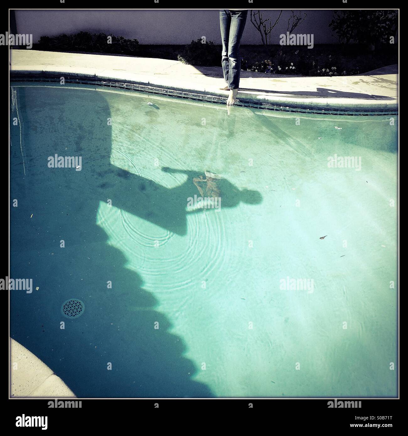 Una sombra en el fondo de una piscina de buceo de una persona fuera de un trampolín. Foto de stock