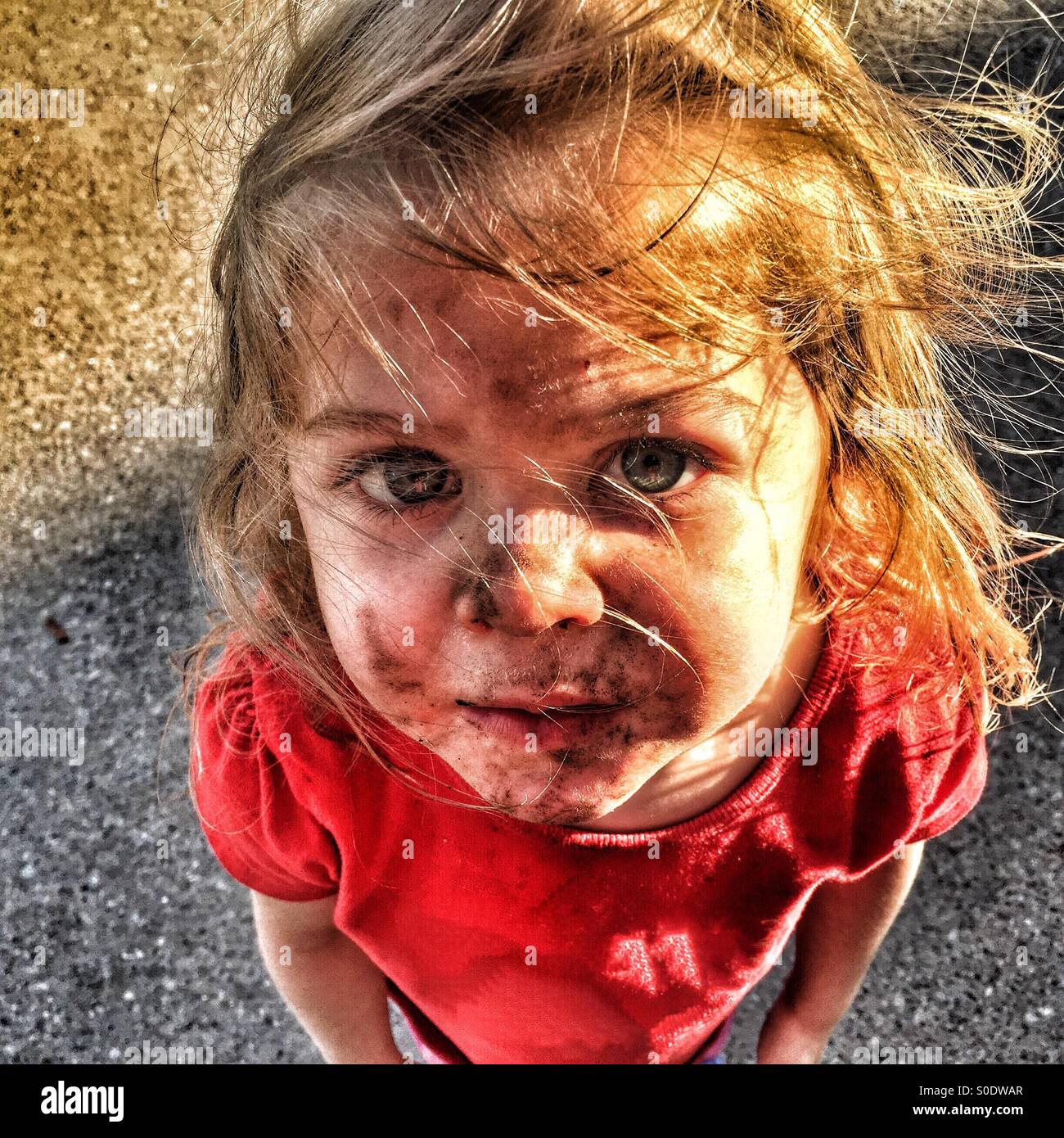 Niño con una cara sucia y el cabello alborotado mirando hacia arriba Foto de stock