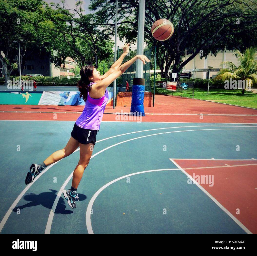 Mujer joven lanzando pelota de baloncesto Fotografía de stock - Alamy