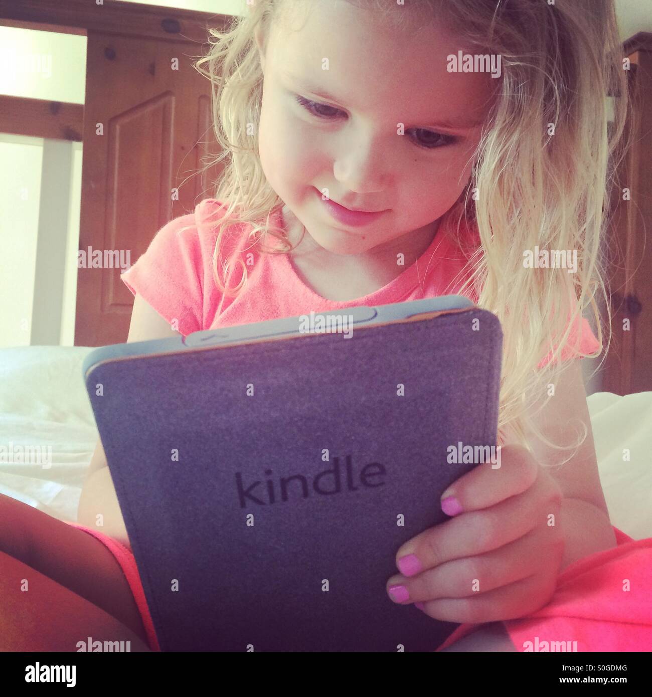 La pequeña niña leyendo un Amazon Kindle Foto de stock