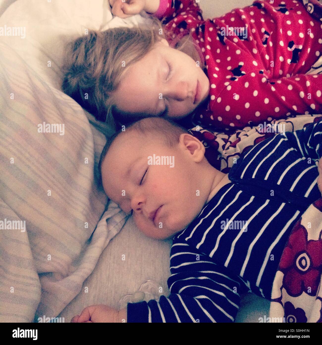 Dos niños durmiendo pacíficamente juntos en la cama con los padres Foto de stock