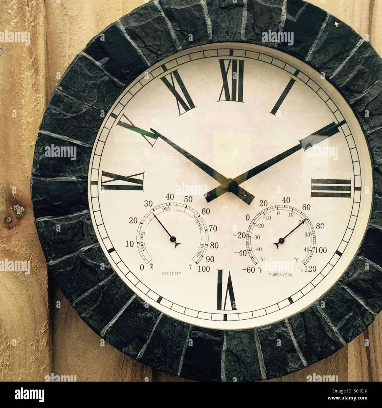 Reloj de temperatura y humedad en un panel de madera antecedentes Foto de stock