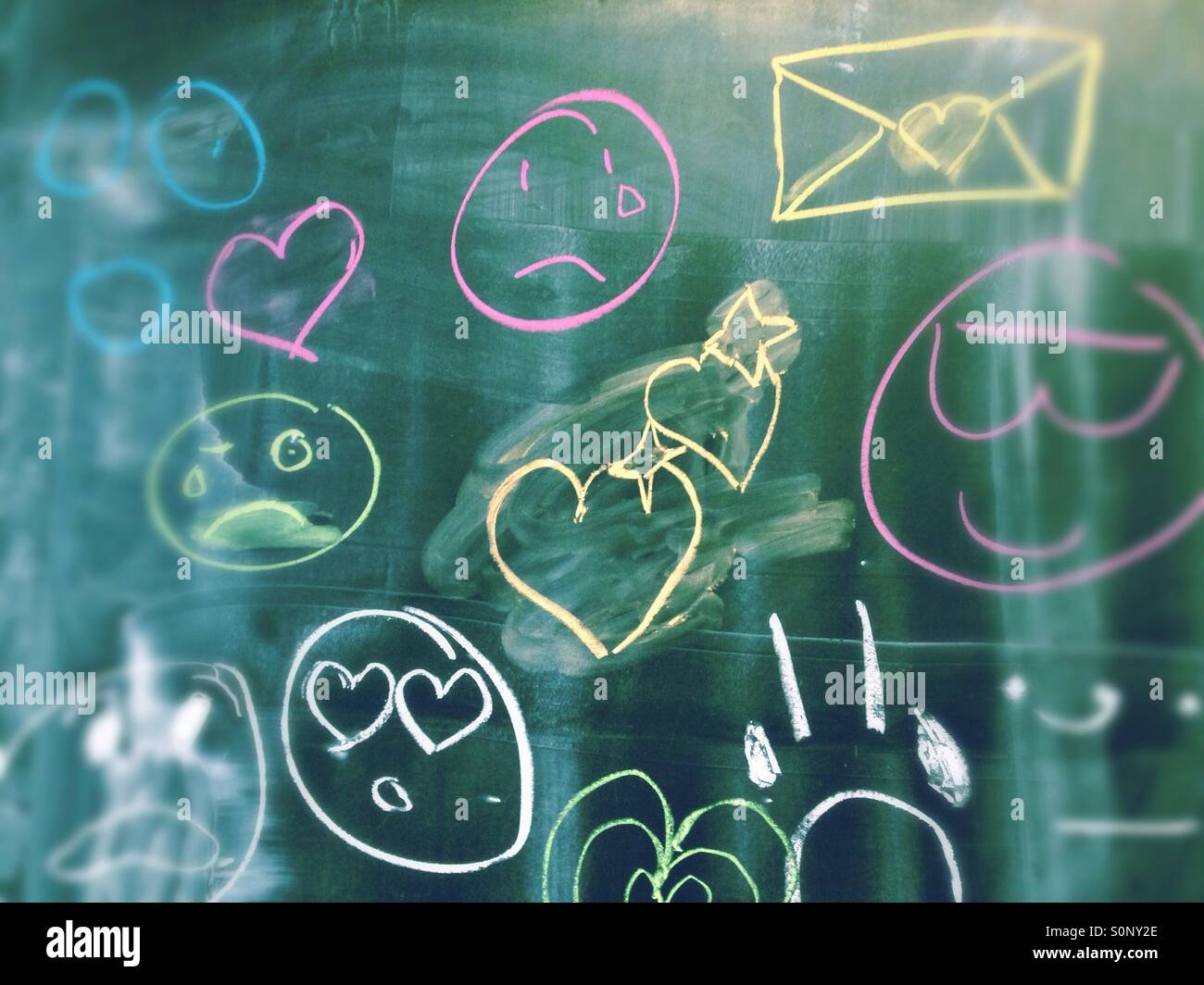 Analógico y emoticonos emojis escrito en una pizarra en la escuela con tiza en diferentes colores. Foto de stock