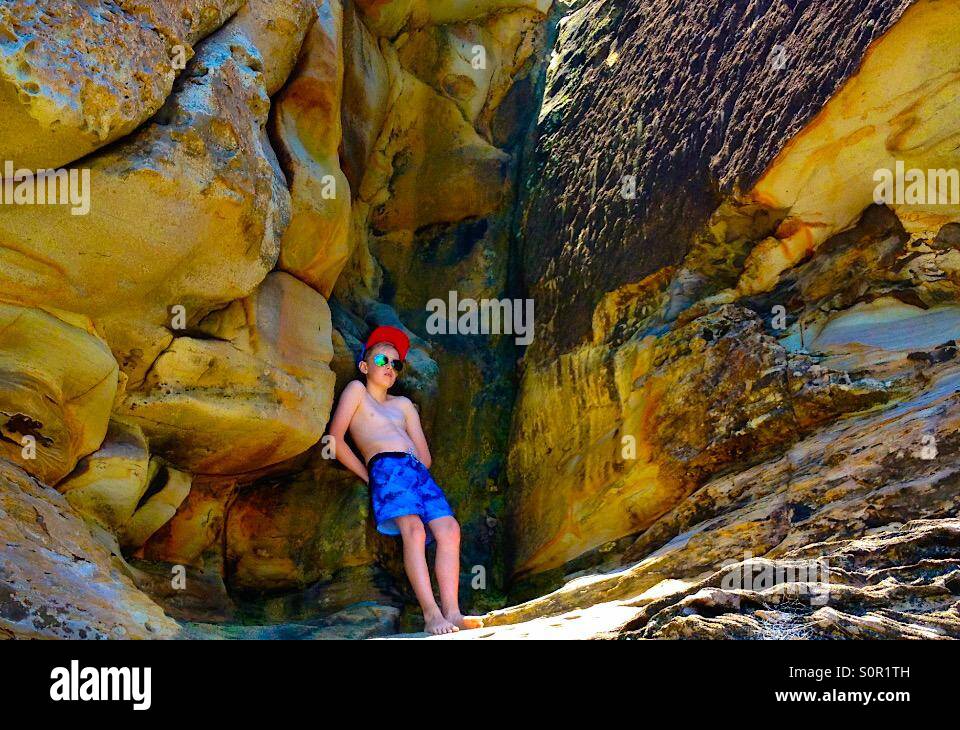Boy relajante en una cueva en las playas del norte Foto de stock
