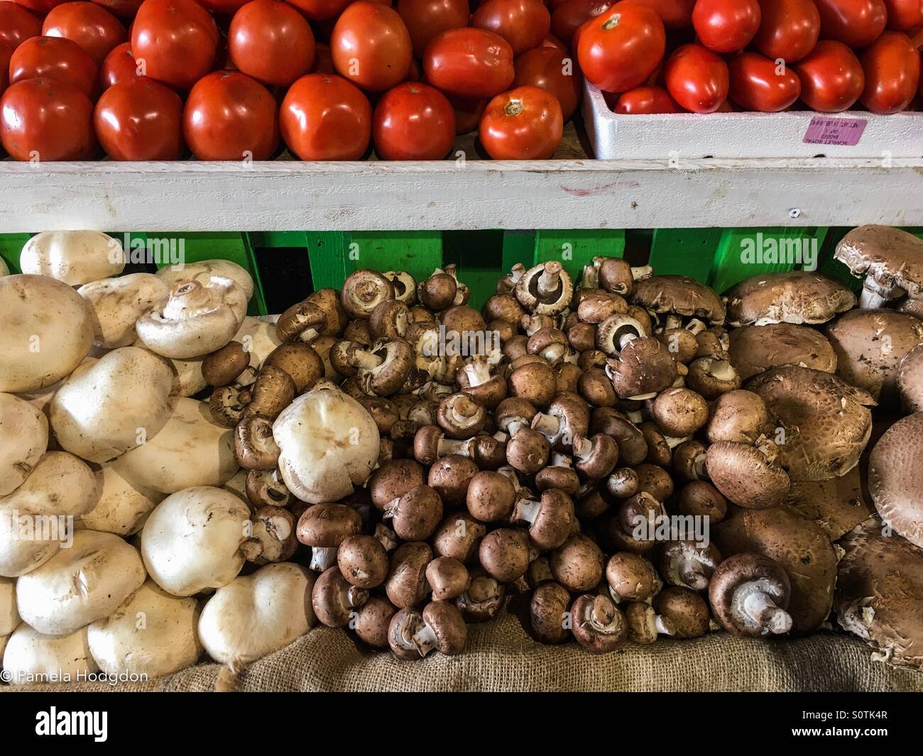Setas y tomates apiladas en un mercado de granjeros. Foto de stock