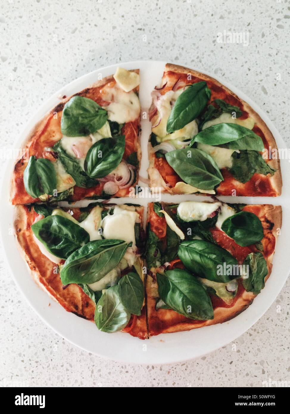 Pizza vegetariana con albahaca fresca cortada en cuartos Foto de stock