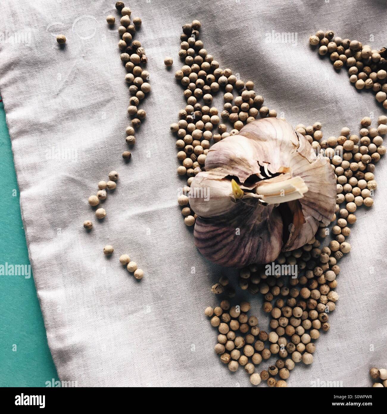 Ajo con granos de pimienta blanca sobre un trozo de tela Foto de stock