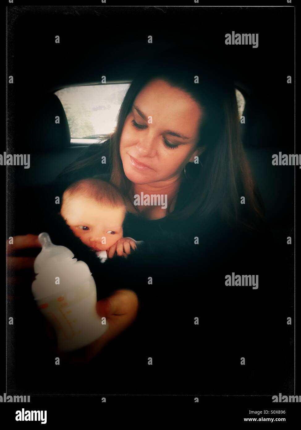Mujer cuidar de un bebé en el asiento trasero de un coche Foto de stock