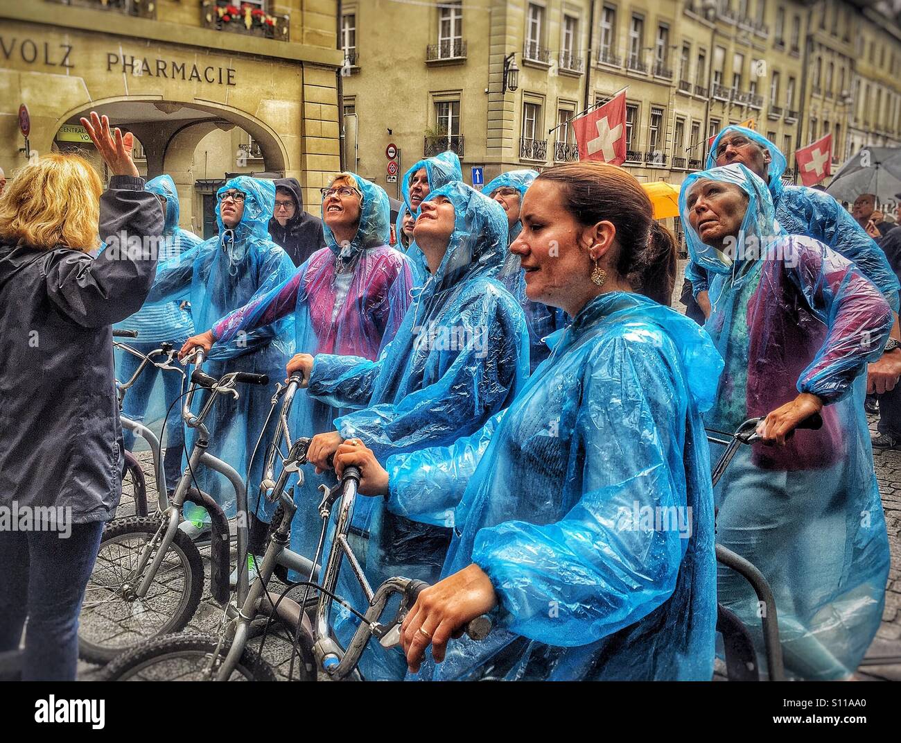 Los turistas enfundados en impermeables azul disfrutar de un scooter tour de Berna, Suiza Foto de stock