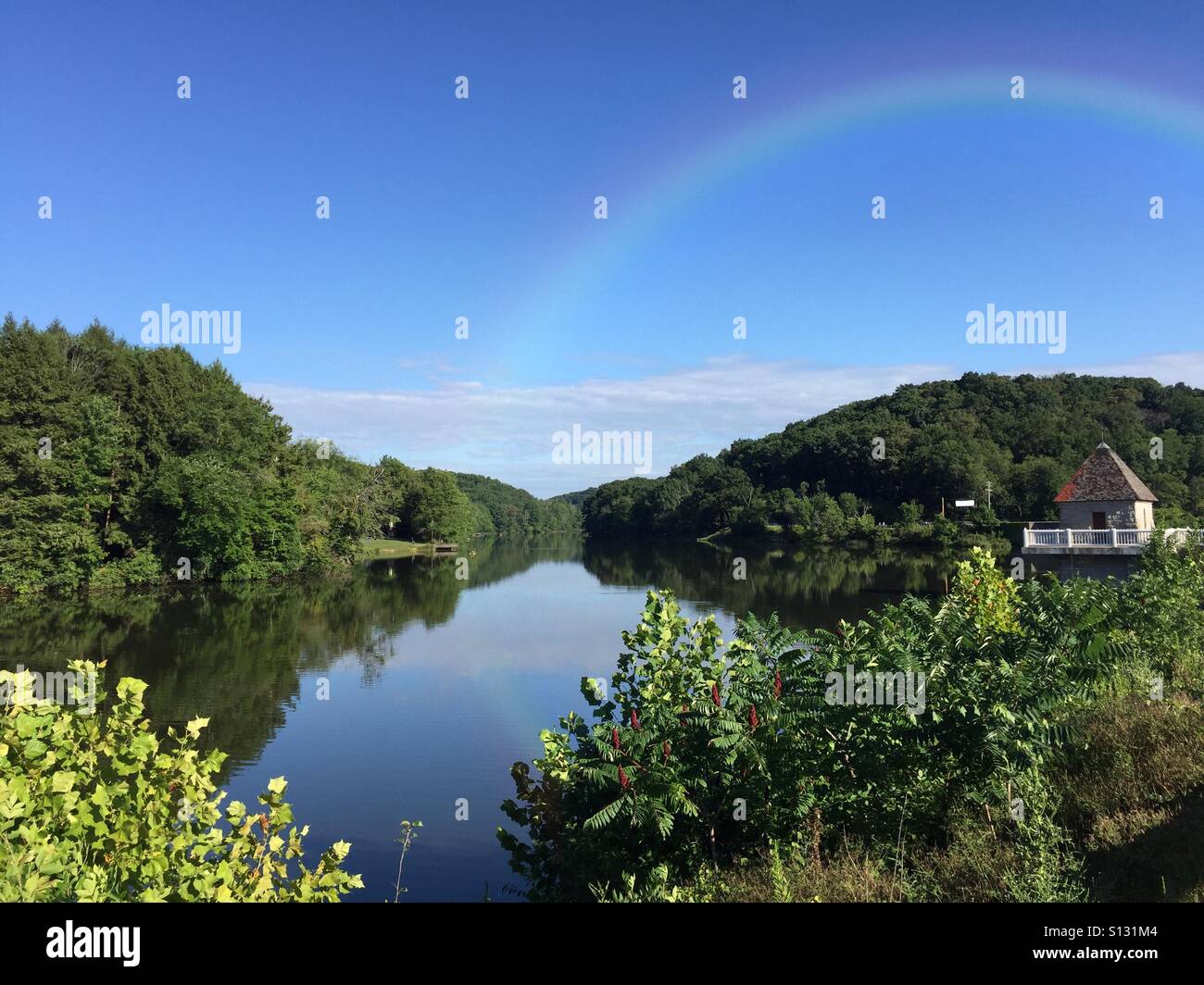 Un hermoso paisaje del lago North Park en Pittsburgh, Pensilvania, EE.UU., con un arco iris contra un cielo azul Foto de stock