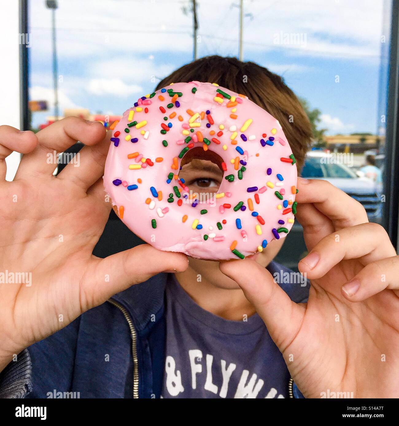 Boy peeping a través del agujero del donut Foto de stock