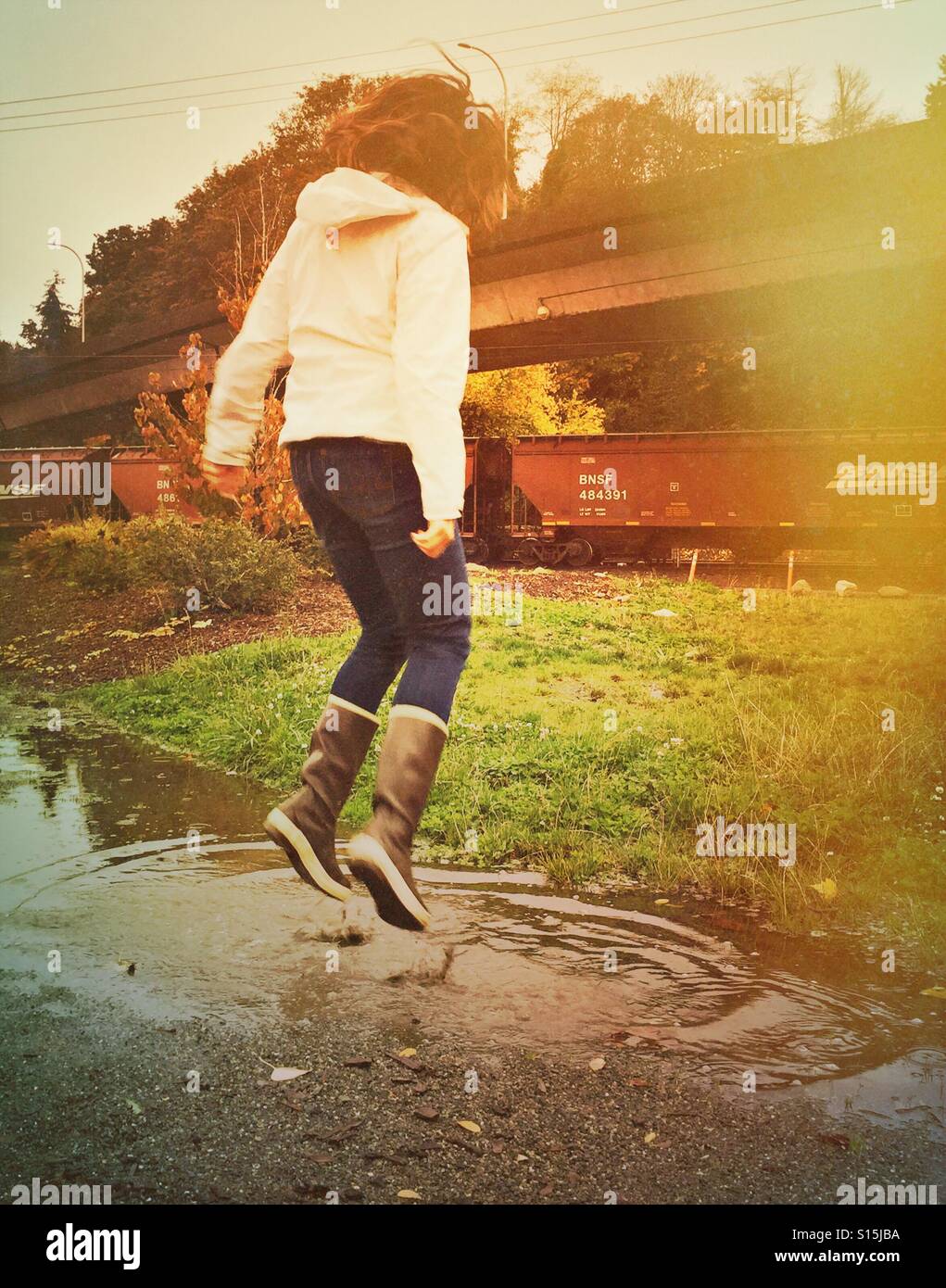 Una divertida mujer vistiendo botas de agua salta en un charco de lluvia en  un día de otoño en el Noroeste Pacífico Fotografía de stock - Alamy