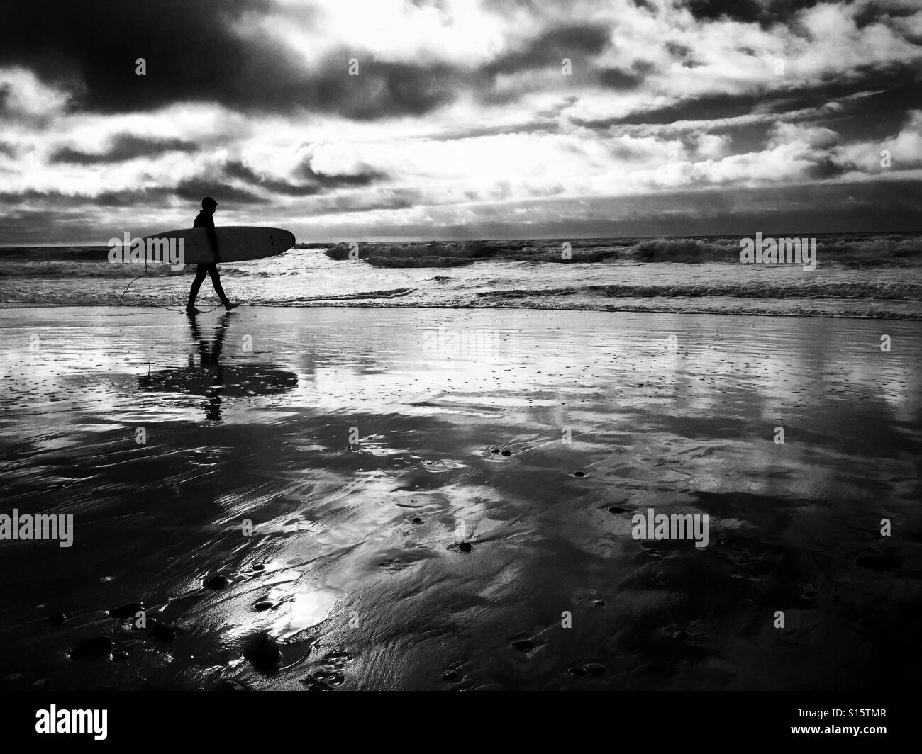 Un surfista lleva su junta mientras camina a lo largo de Freshwater West Beach en el sur de Gales, octubre de 2016 Foto de stock