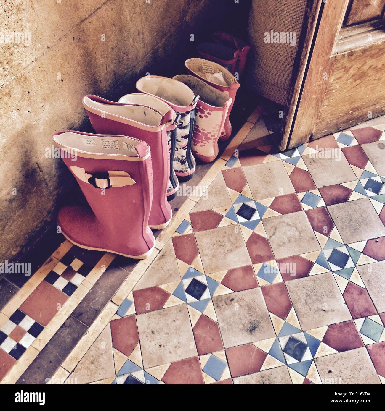 Una familia de botas Wellington alineadas en la puerta de una casa de campo - hogar familiar - vida rural - estilo de vida familiar saludable al aire libre Foto de stock