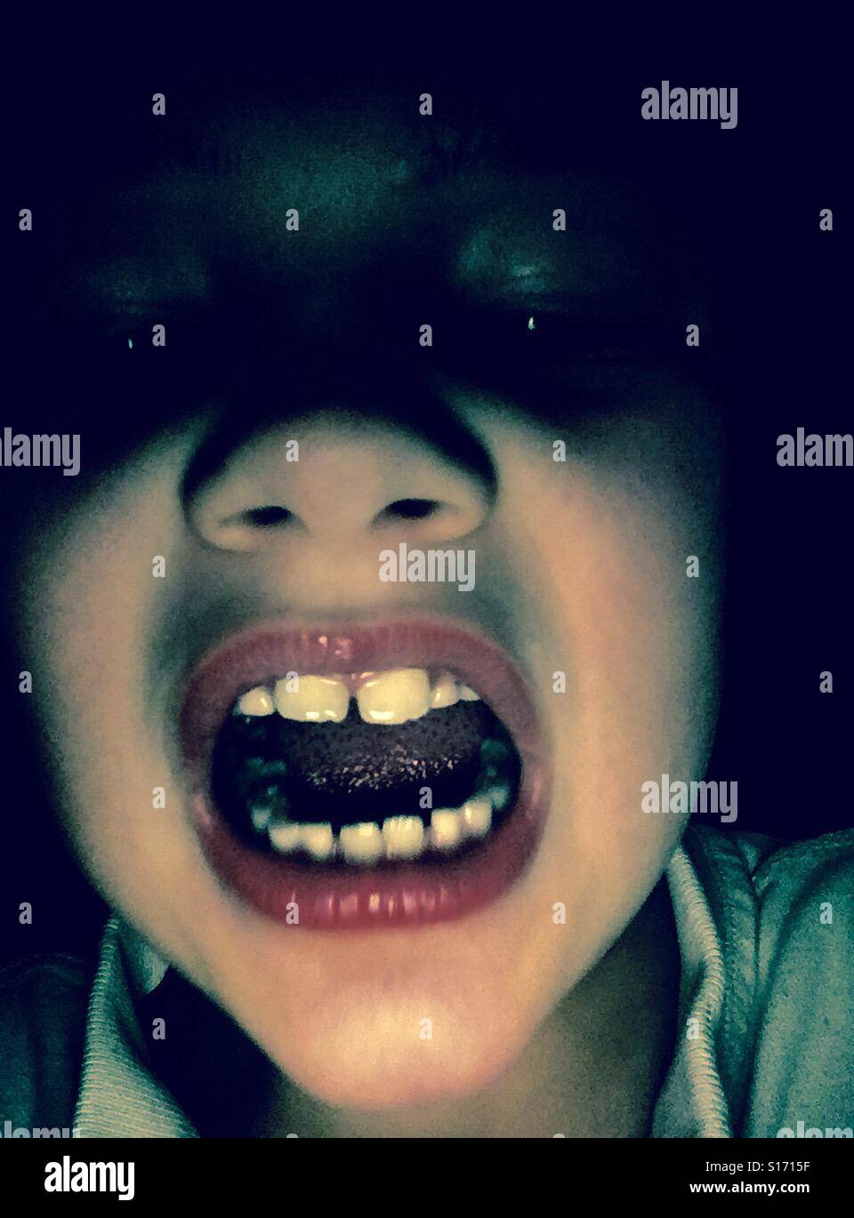 Niño en la oscuridad con la boca abierta Foto de stock