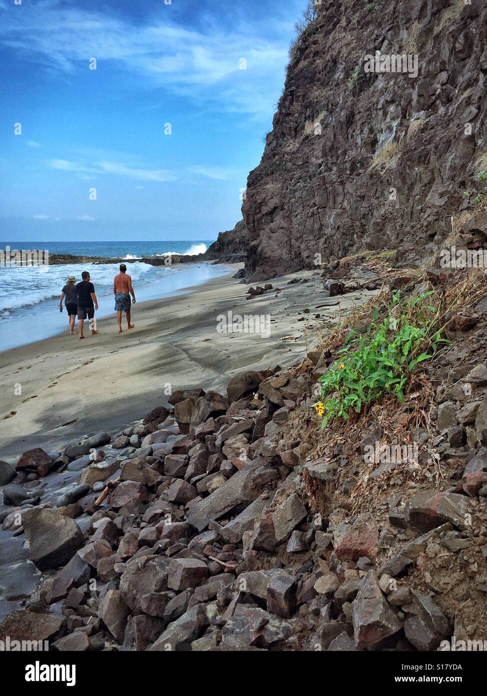La gente camina en la playa junto a una ladera rocosa en Nayarit, México. Foto de stock