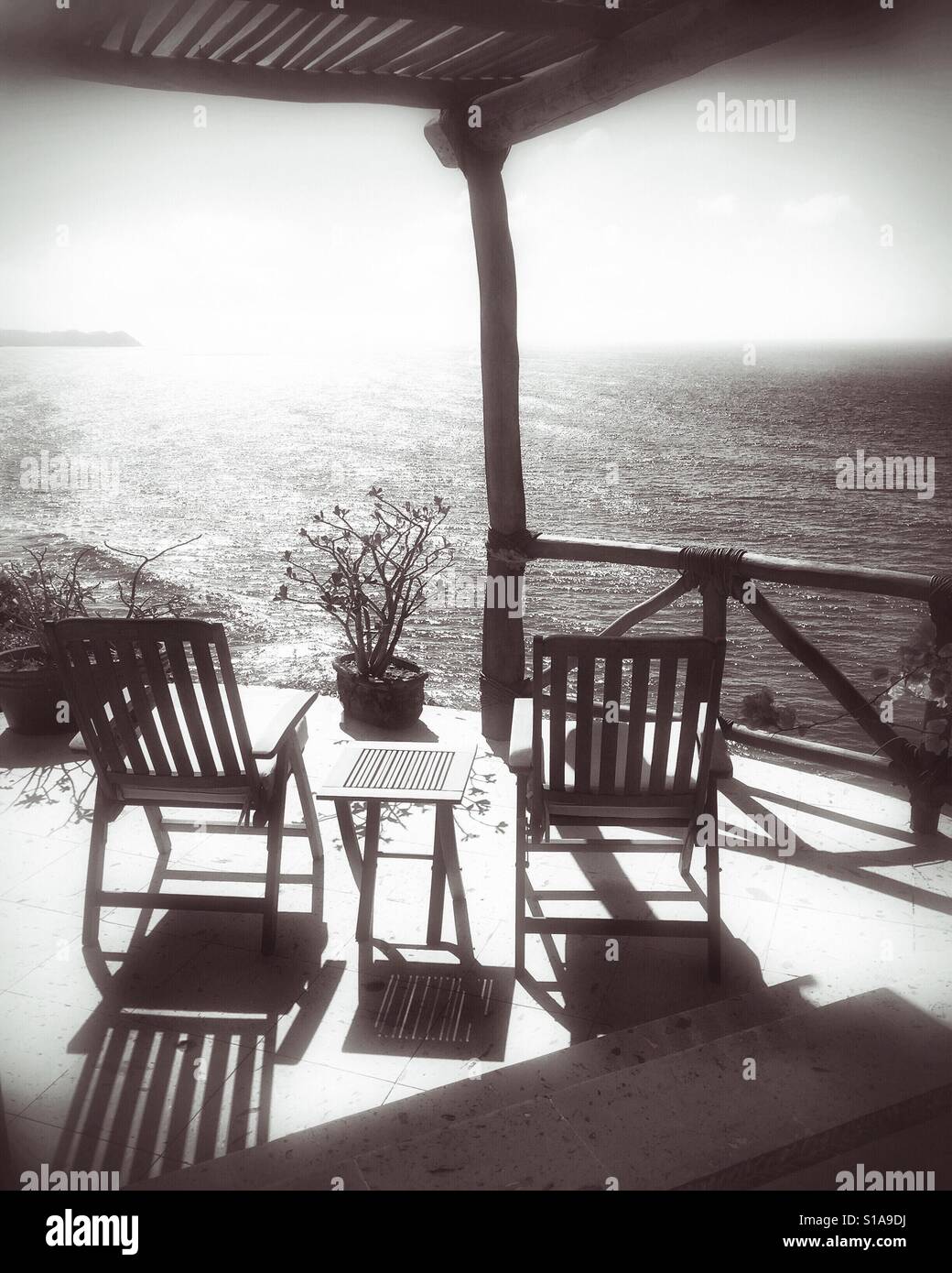 Sol y sombras añaden belleza y profundidad al patio lleno de muebles de madera de teca con vistas al Océano Pacífico en Nayarit, México. Foto de stock