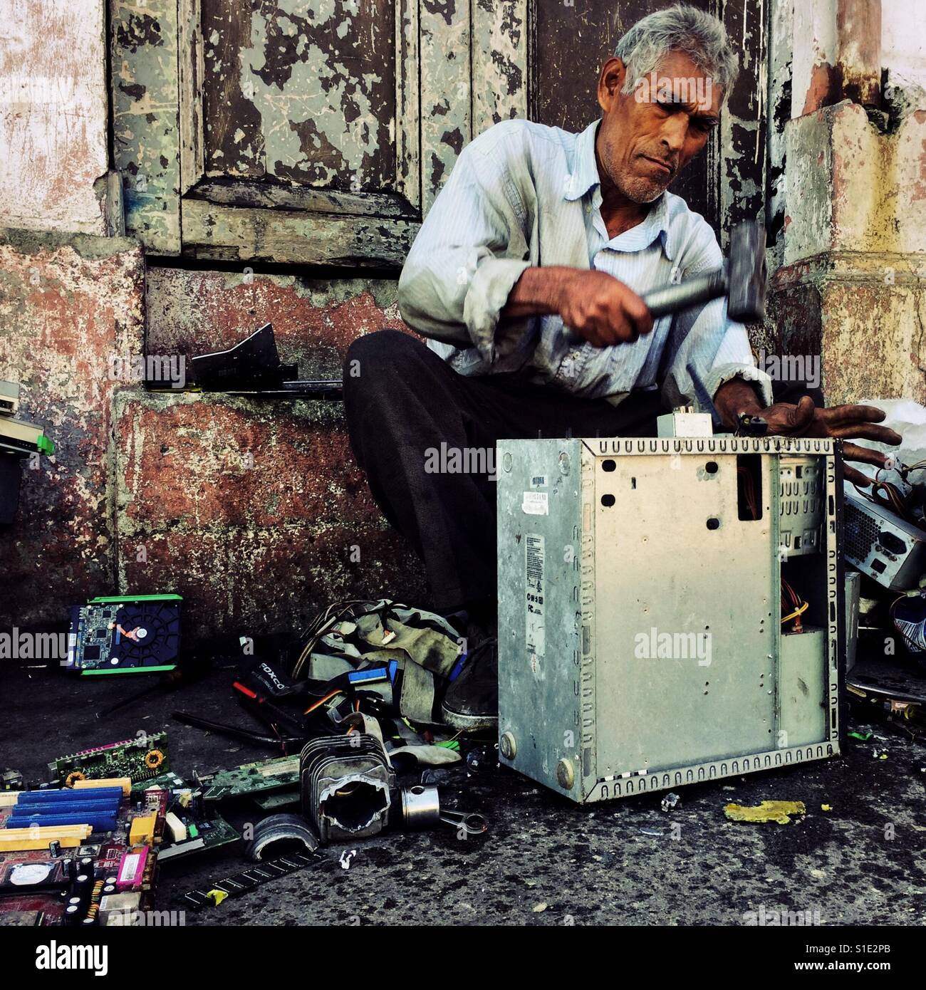 Un reciclador salvadoreño desmantela un viejo ordenador de sobremesa para obtener valiosos componentes y metales en la calle de San Salvador, El Salvador, 14 de noviembre de 2016. Foto de stock
