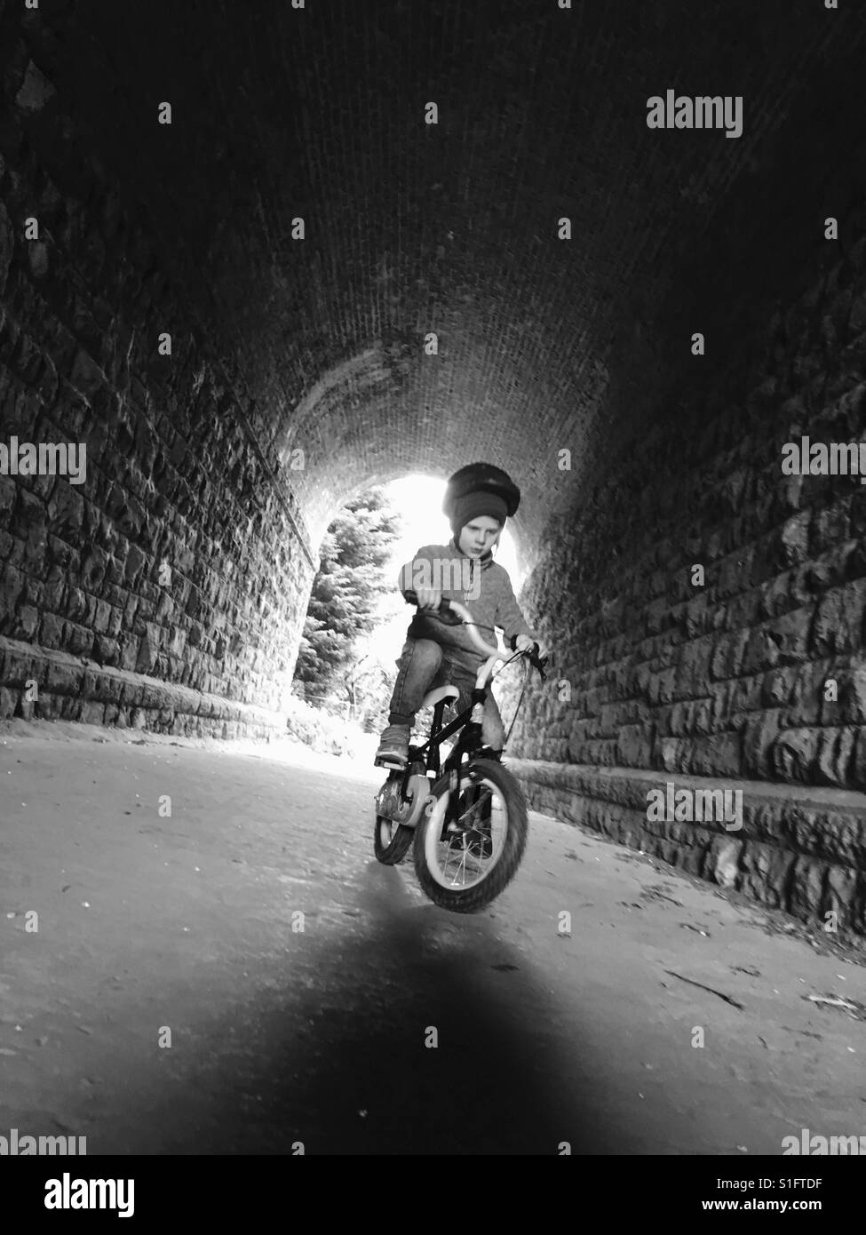 Boy a montar una bicicleta a través del túnel Foto de stock